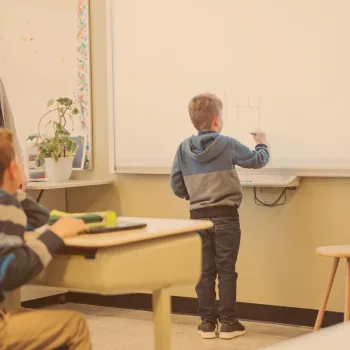 Élève écrivant au tableau interactif devant sa classe
