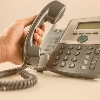 Main décrochant le combiné d'un téléphone de bureau