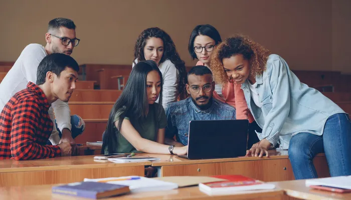 Étudiants réunis autour d'un ordinateur portable en classe