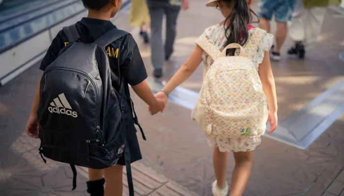 Deux enfants avec leur cartable se tenant la main